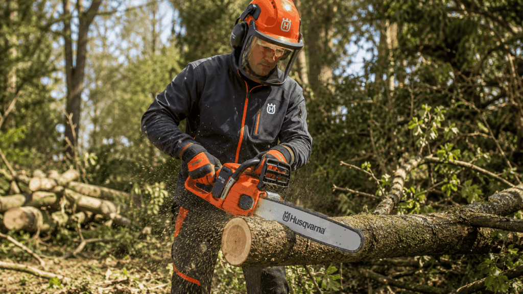 un homme utulisant sa tronçonneuse à batterie de la marque husqvarna